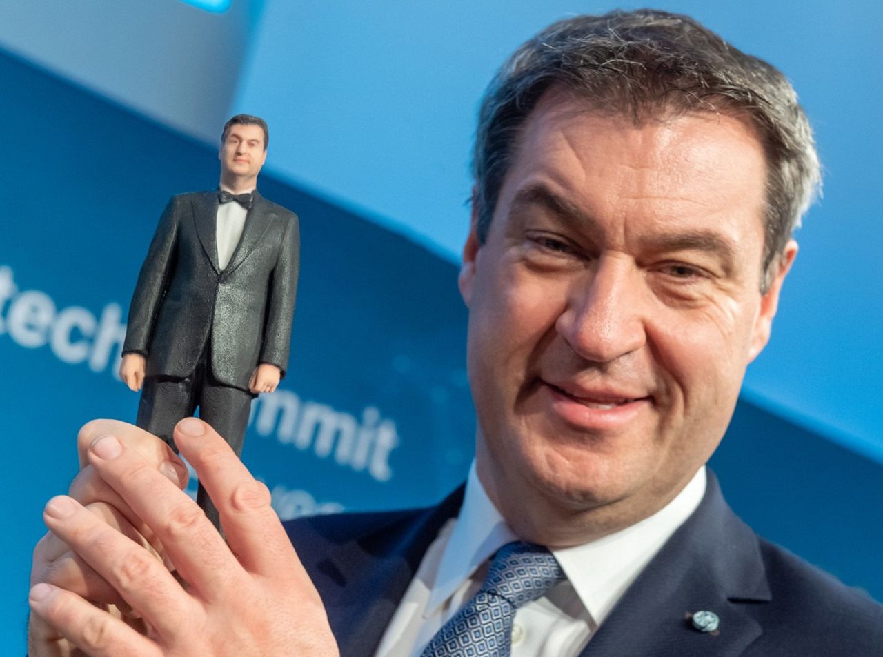 Markus Söder shows a small 3-D figure of himself.