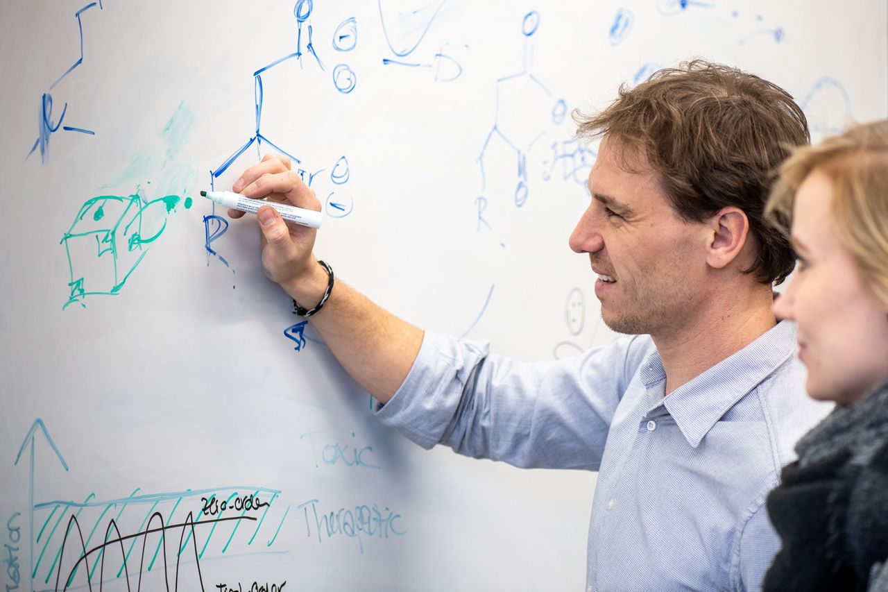 Prof. Job Boekhoven, who stands at a whiteboard and writes down various graphs and chemical compounds.