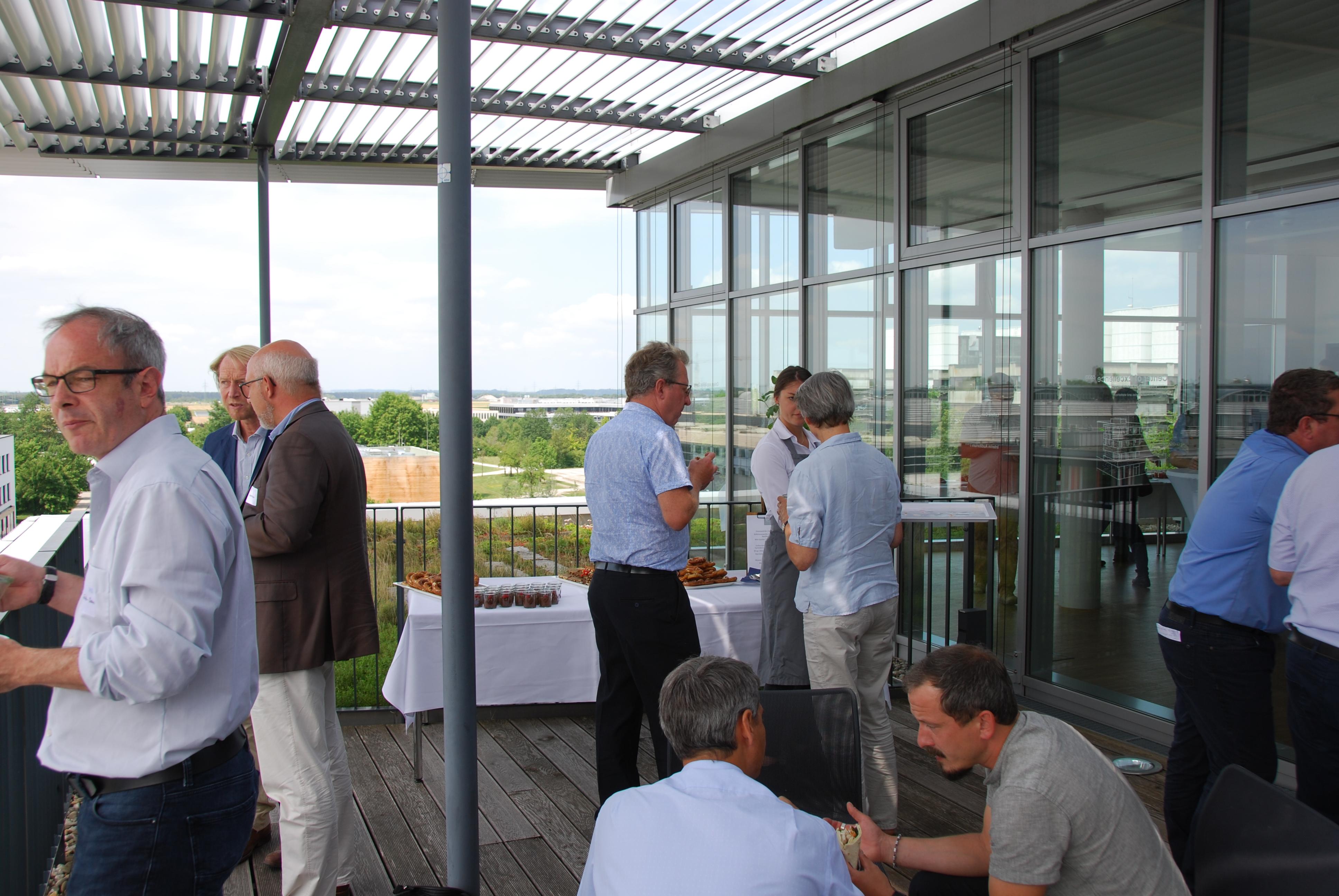 Several small groups of participants chatting on the roof top terrace during lunch break. 